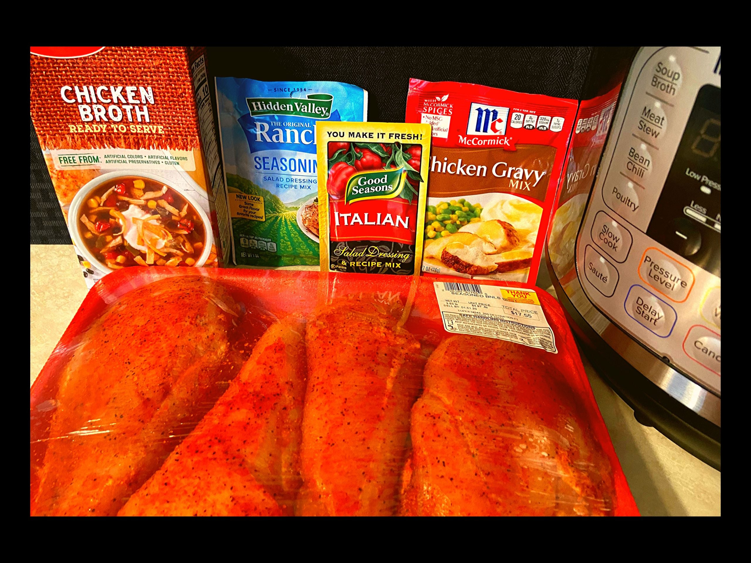 A kitchen counter top with a packet of raw chicken breast, container of chicken broth, packet of ranch dressing, packet of Italian dressing, packet of chicken gravy, and an Instant Pot.